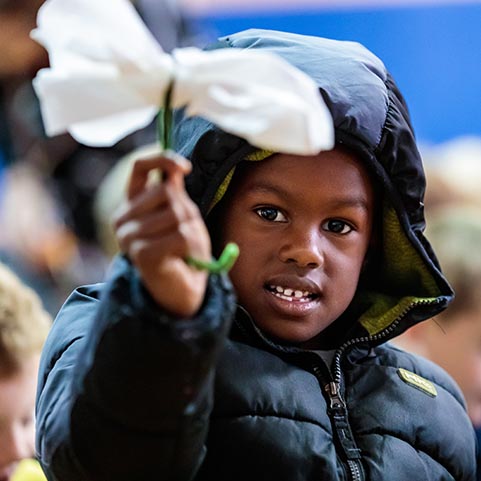  photo of a boy with a coat on and holding a flower